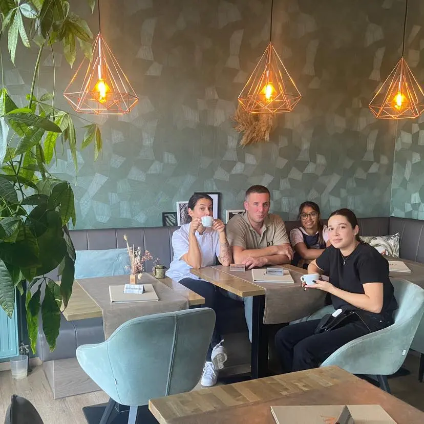 Interieur van Brasserie De Wissel met koperen hanglampen, groene wand en velours stoelen